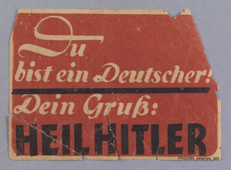 Etiquette encollée : "Du bist ein Deutscher ! Dein Gruss : Heil Hitler"  - cote Archives d'Alsace - Colmar estampe 365